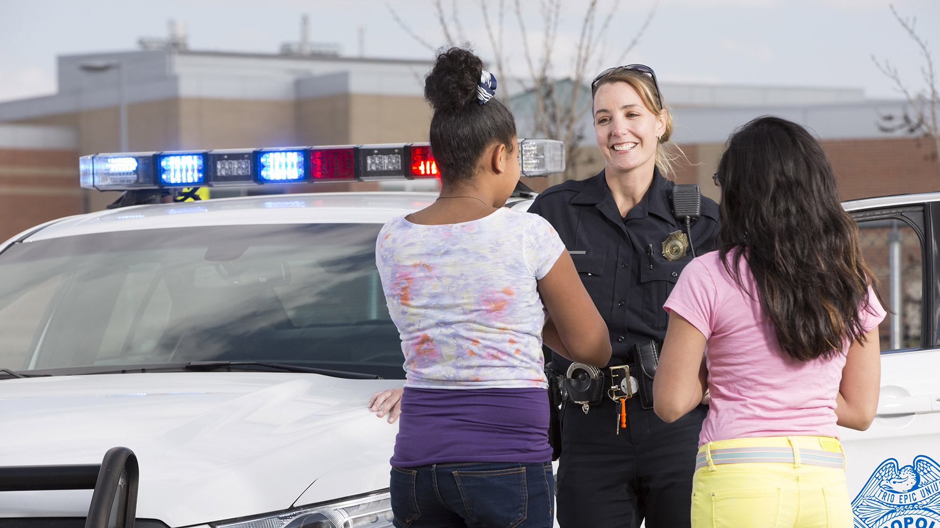 A police officer smiling at two teenagers who have their back to the camera