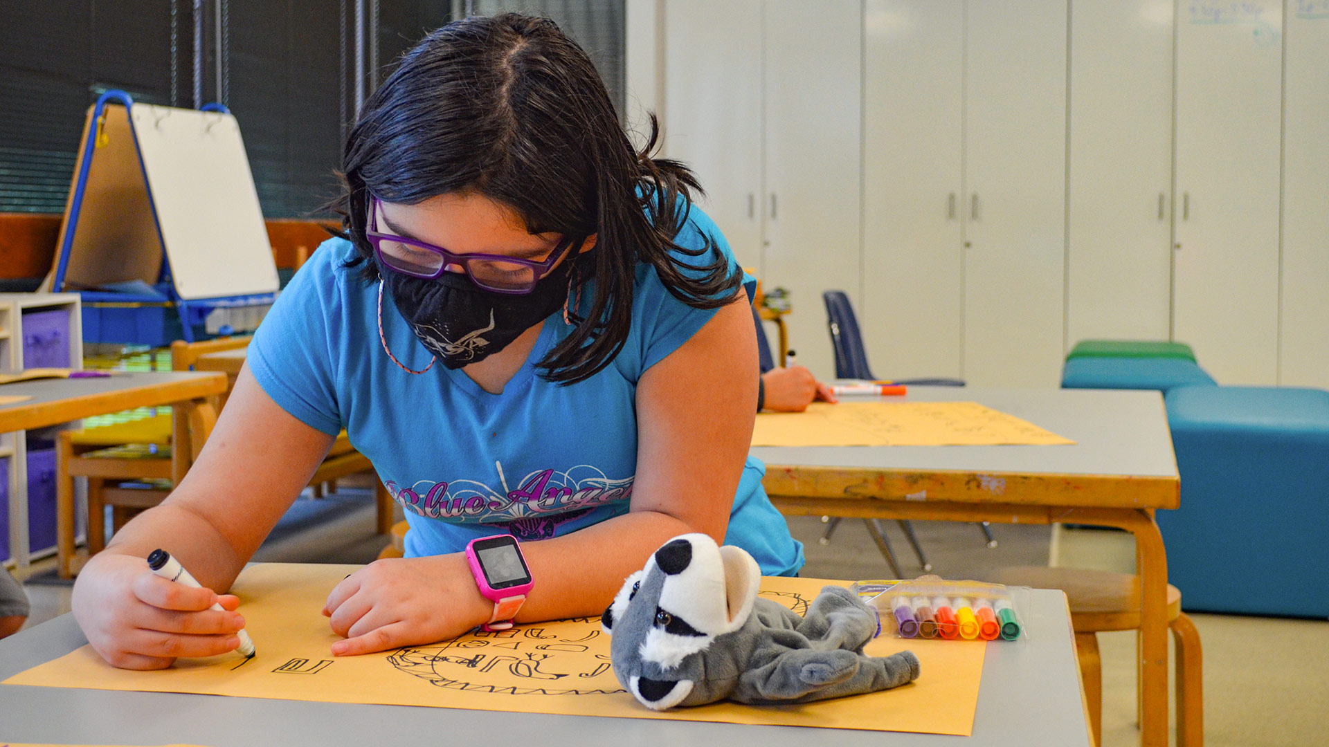 A masked student draws in an art classroom
