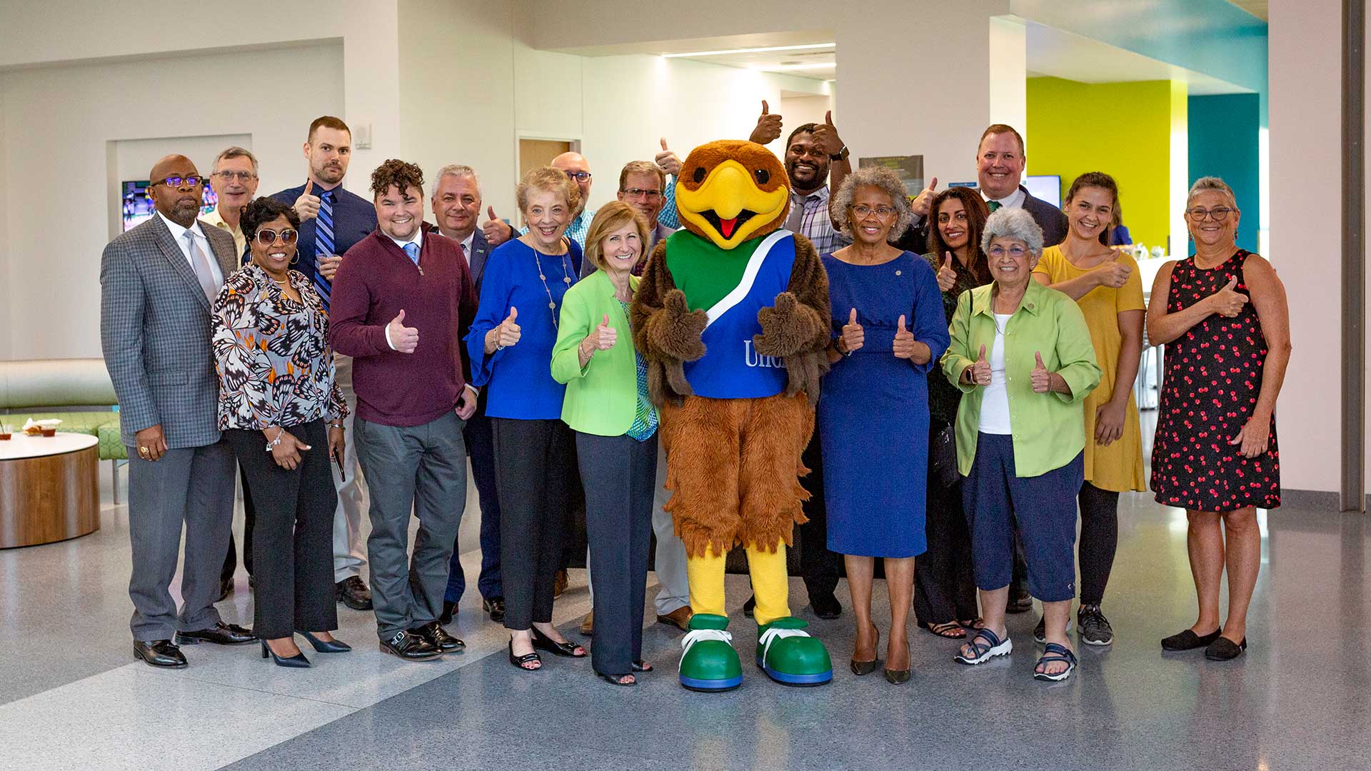 Hunter the Hawk, President Ira K. Blake, and a gathering of students, faculty, and staff giving a thumb's up sign