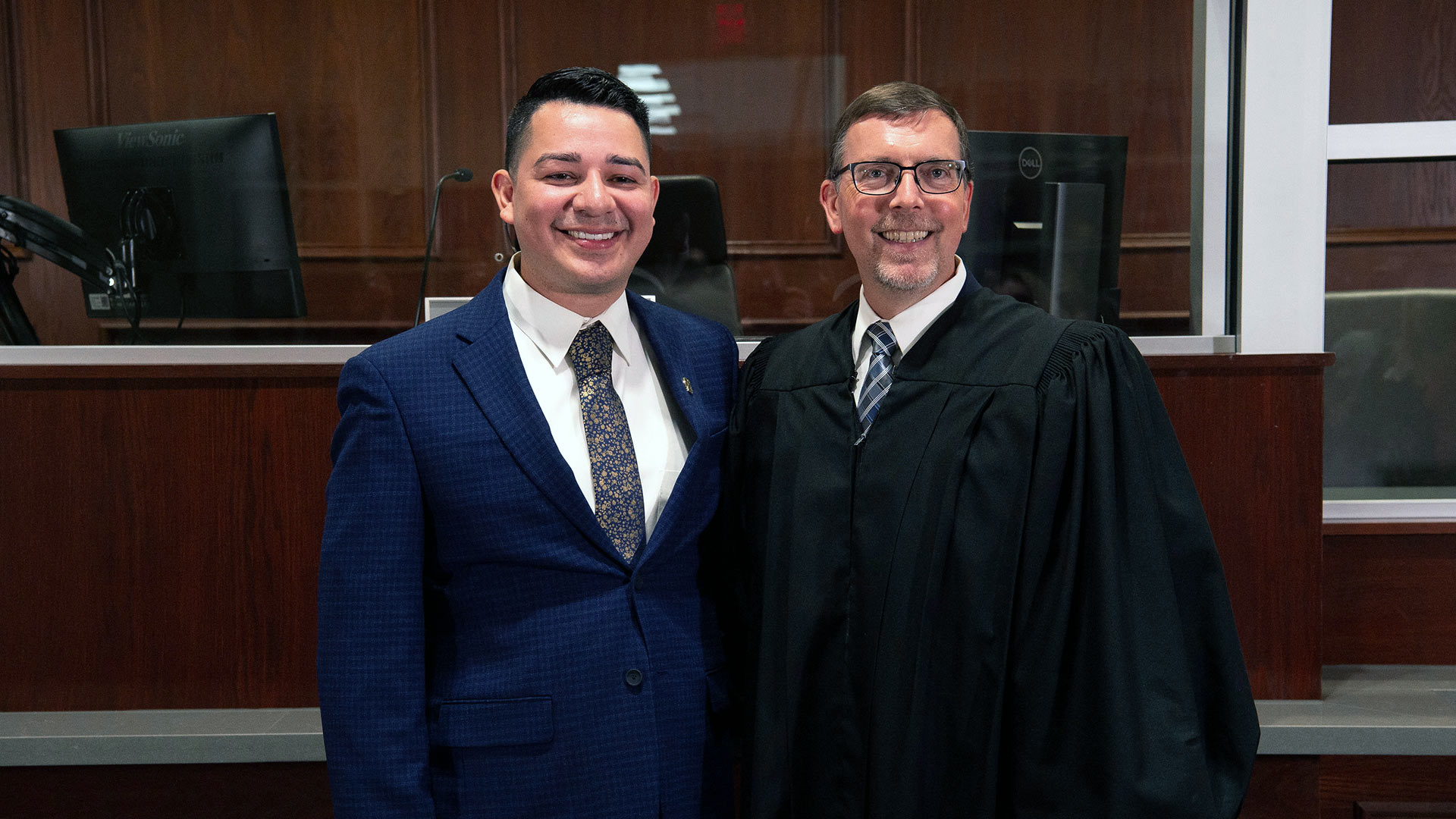 Jonathan Estrada and Jim Evans smiling in a courtroom