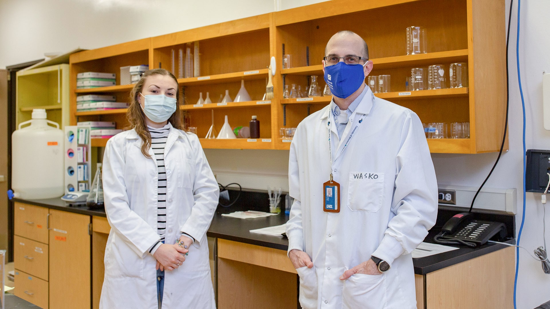 A student and professor in lab coats at a UHCL science lab